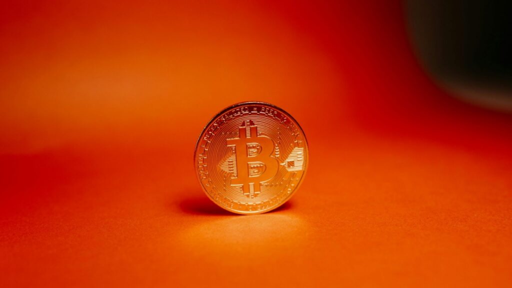 Physical bitcoin coin on orange background